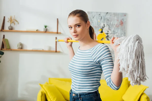 Hermosa mujer mirando a la cámara mientras sostiene la fregona en casa — Stock Photo