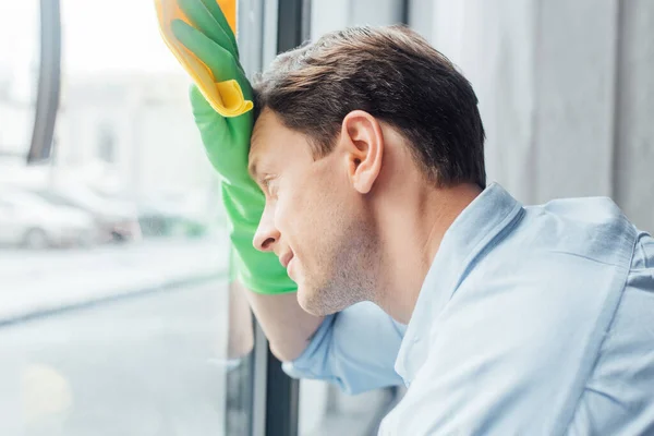 Side view of man with rag cleaning glass of window — Stock Photo