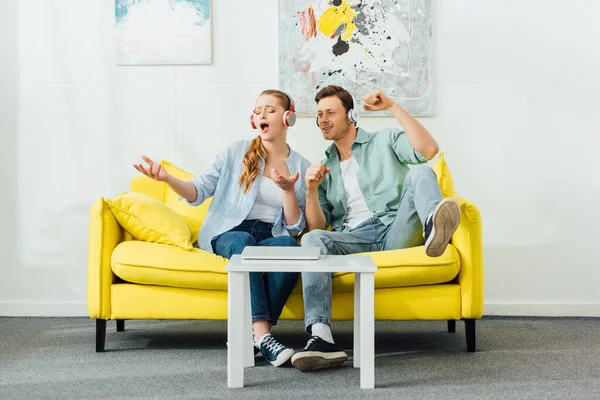 Mädchen singt nahe Freund mit Kopfhörer auf Couch im Wohnzimmer — Stockfoto