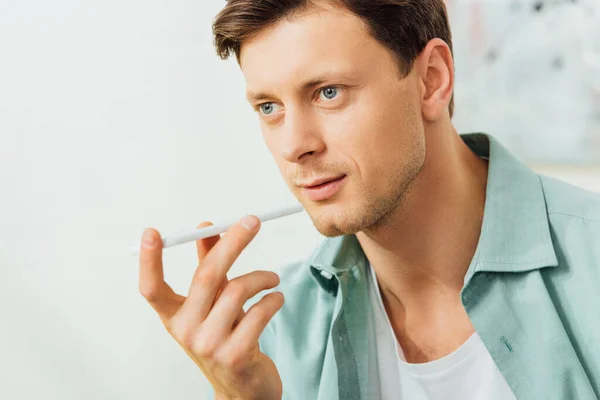 Schöner Mann mit Kopfhörer, während er zu Hause auf dem Smartphone spricht — Stockfoto