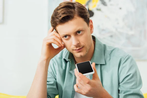 Pensive man using speakerphone while talking on smartphone — Stock Photo