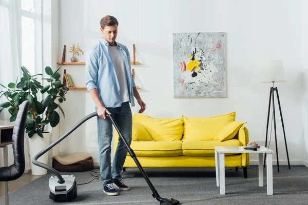 Homme nettoyage tapis avec aspirateur dans le salon — Photo de stock