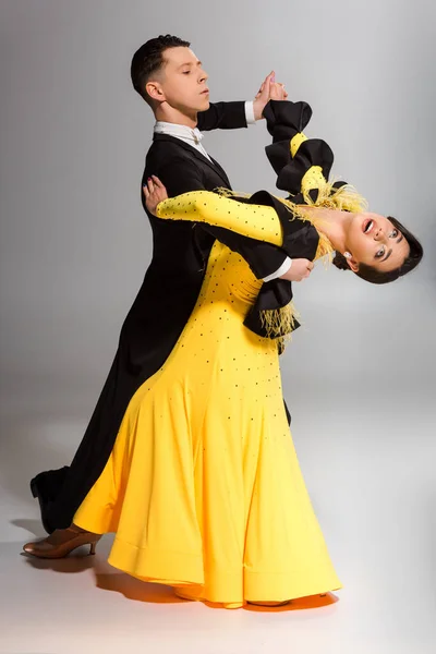 Élégant jeune couple de danseurs de salon dansant sur gris — Photo de stock