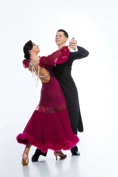 Elegante pareja joven de bailarines de salón en vestido rojo en traje bailando en blanco - foto de stock