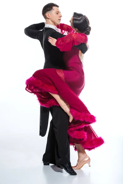 Elegant young couple of ballroom dancers in red dress in suit dancing on white — Stock Photo