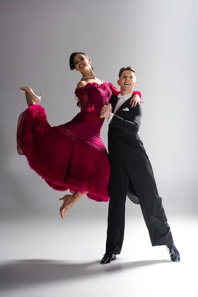 Элегантная молодая пара танцовщиц в красном платье в костюме, танцующая на белом — стоковое фото