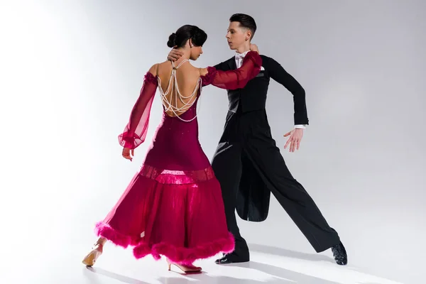 Elegante jovem casal de dançarinos de salão em vestido vermelho em terno dançando no branco — Fotografia de Stock