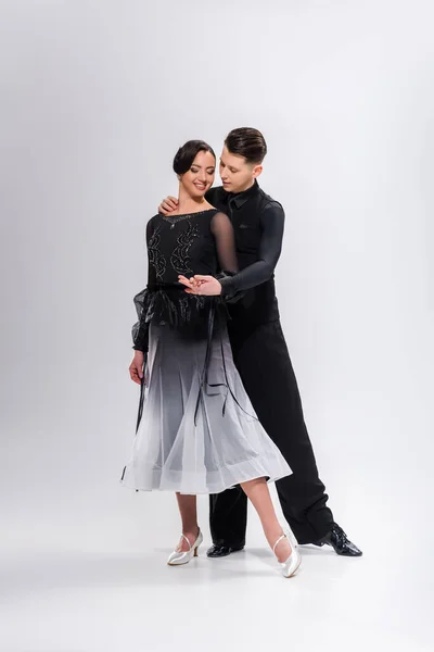 Elegante pareja joven de bailarines de salón en traje negro bailando en blanco - foto de stock