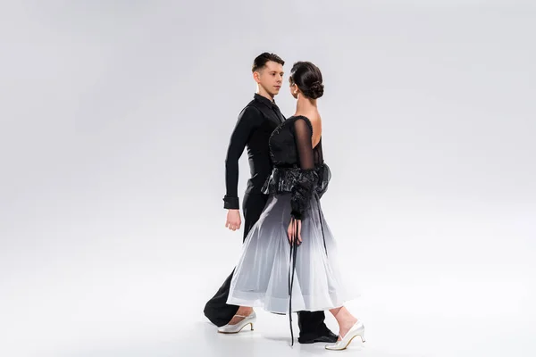 Elegant young couple of ballroom dancers in black outfit dancing on white — Stock Photo