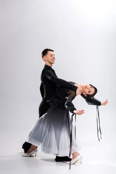 Elegante pareja joven de bailarines de salón en traje negro bailando en blanco - foto de stock