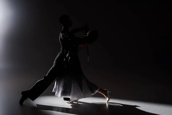 Elegantes junges Tanzpaar in schwarzem Outfit, das in Dunkelheit tanzt — Stockfoto