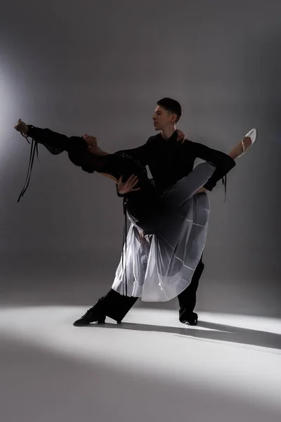 Elegante giovane coppia di ballerini da sala in abito nero che ballano al buio — Foto stock