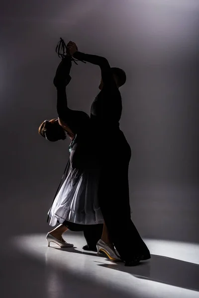 Elegant young couple of ballroom dancers in black outfit dancing in dark — Stock Photo