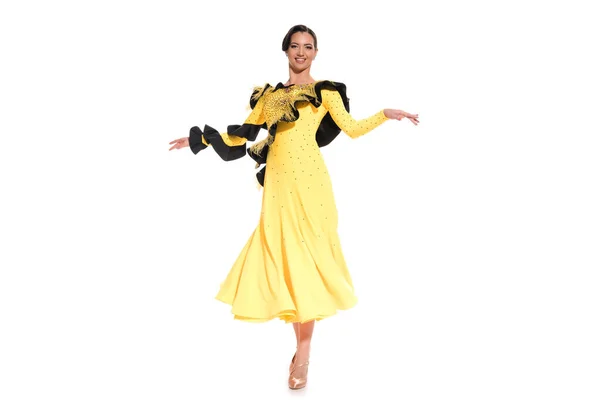 Улыбающаяся элегантная молодая танцовщица в желтом платье, танцующая отдельно на белом — стоковое фото