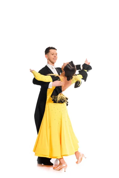 Élégant jeune couple de danseurs de salon en robe jaune et costume noir dansant sur blanc — Photo de stock