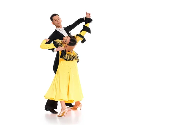 Élégant jeune couple de danseurs de salon en robe jaune et costume noir dansant sur blanc — Photo de stock