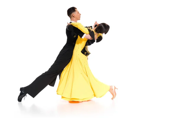 Elegante giovane coppia di ballerini da sala in abito giallo e abito nero che ballano su bianco — Foto stock