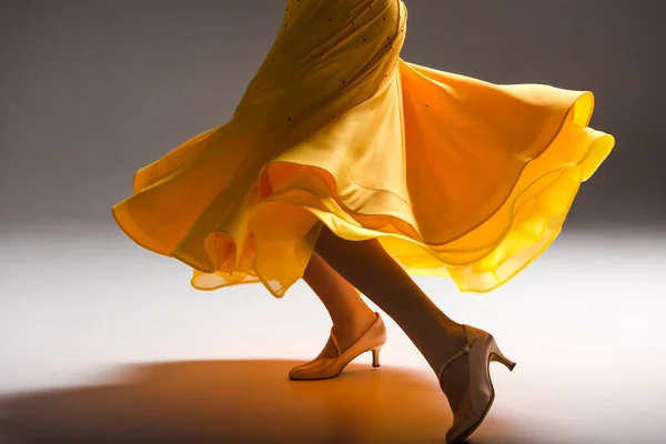 Vista ritagliata di elegante giovane ballerina sala da ballo in abito giallo ballare al buio — Foto stock