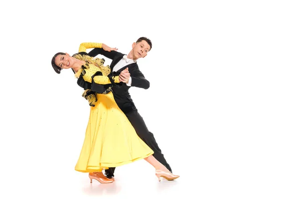 Smiling elegant young couple of ballroom dancers in yellow dress and black suit dancing on white — Stock Photo