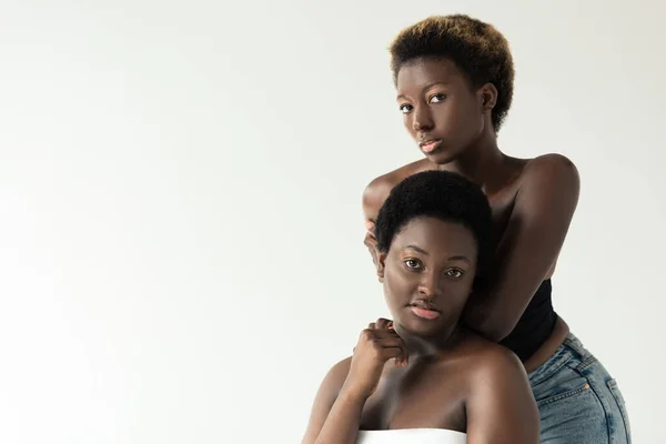 Mujeres afroamericanas atractivas en las tapas de pie aislado en gris - foto de stock