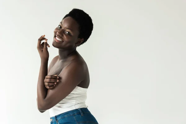 Fröhliche afrikanisch-amerikanische Mädchen in Jeans und weißem Top isoliert auf grau — Stockfoto