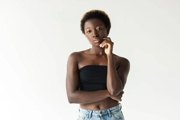 Fille afro-américaine réfléchie en jeans et haut noir isolé sur gris — Photo de stock