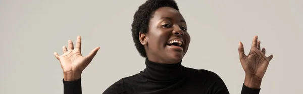 Panoramic shot of cheerful african american woman in black turtleneck isolated on grey — Stock Photo
