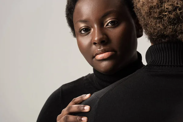 Афроамериканські жінки в чорних черепах обіймаються ізольовано на сірому — стокове фото