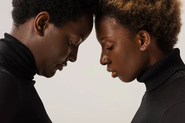 African american women in black turtlenecks touching foreheads isolated on grey — Stock Photo