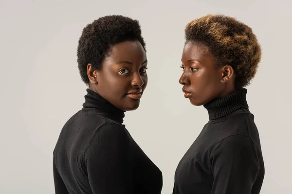 Mujeres afroamericanas en cuellos altos negros aisladas en gris - foto de stock