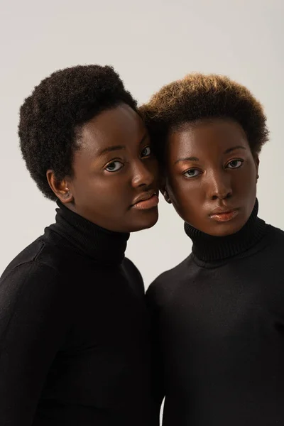Mulheres americanas africanas atraentes em golas pretas isoladas em cinza — Fotografia de Stock