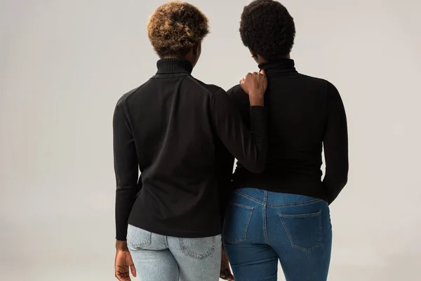 Vue arrière d'amis afro-américains en col roulé noir isolé sur gris — Photo de stock