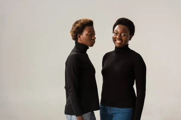 Chicas afroamericanas en cuellos altos negros aisladas en gris - foto de stock