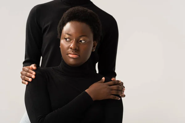 African american friends in black turtlenecks holding hands isolated on grey — Stock Photo