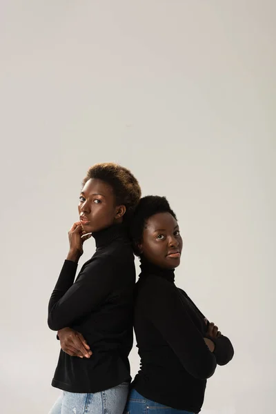 Meninas americanas africanas pensativo em turtlenecks pretos de pé de volta para trás isolado em cinza — Fotografia de Stock