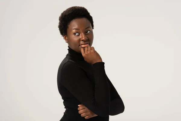 Thoughtful smiling african american woman in black turtleneck isolated on grey — Stock Photo