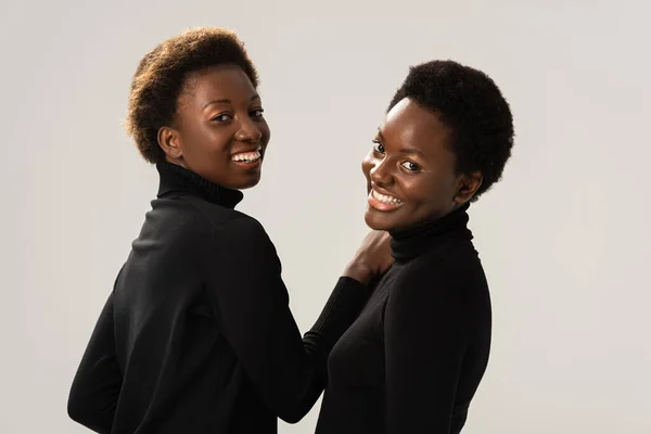 Felici ragazze africane americane in dolcevita neri isolati su grigio — Foto stock