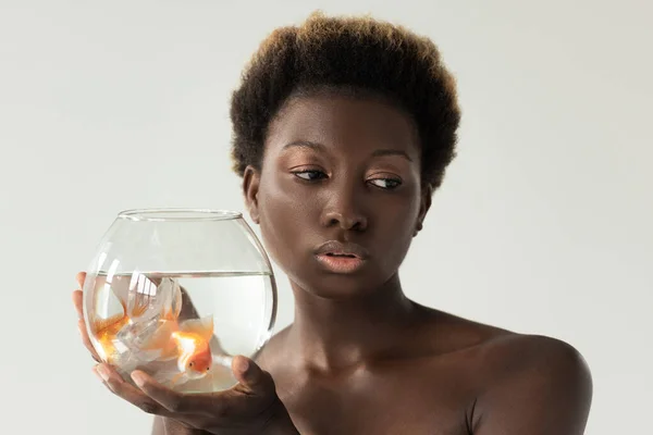 Nackte afrikanisch-amerikanische Mädchen hält Aquarium mit Fischen isoliert auf grau — Stockfoto