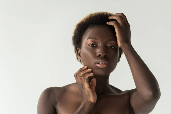 Приваблива чуттєва гола афроамериканська дівчина торкається обличчя ізольовано на сірому — стокове фото