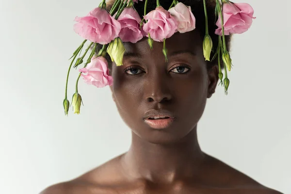 Attractive naked african american woman with pink eustoma flowers isolated on grey — Stock Photo