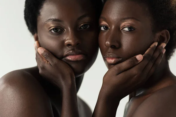 Chicas afroamericanas desnudas abrazando y mirando a la cámara aislada en gris - foto de stock