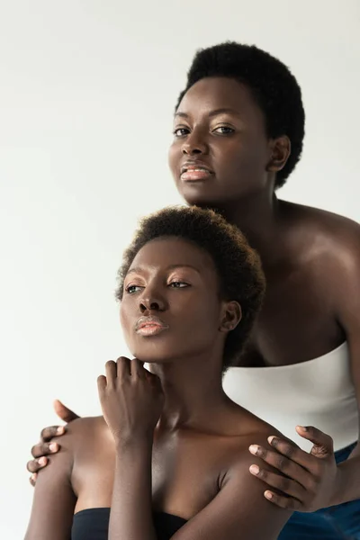 Copines afro-américaines réfléchies en hauts isolés sur gris — Photo de stock