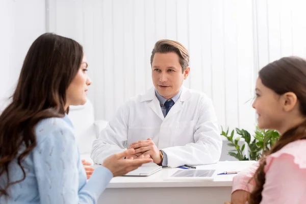 Madre e hija hablando con ent médico durante la consulta - foto de stock