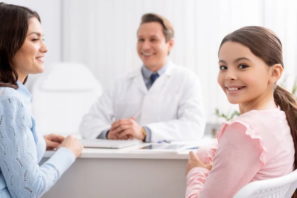 Selective focus of happy mother and daughter near smiling otolaryngologist — Stock Photo