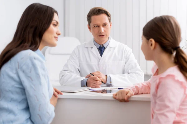 Beau médecin consultant mère et fille en clinique — Photo de stock