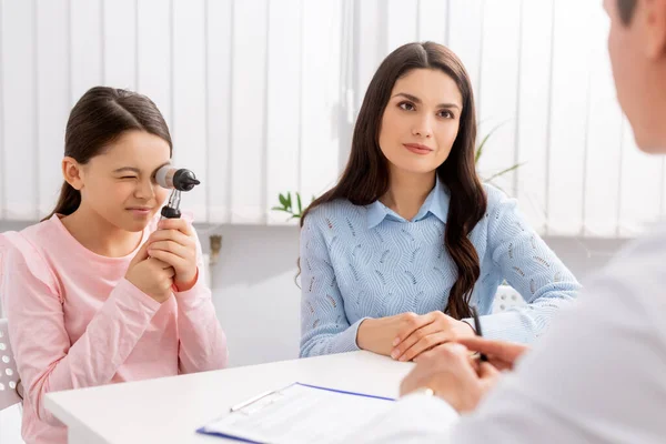 Vista ritagliata del medico ent vicino alla donna con simpatico otoscopio bambino in possesso — Foto stock