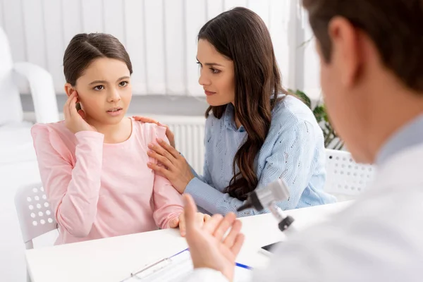 Vue recadrée du médecin ent, et la femme apaisante fille toucher oreille — Photo de stock