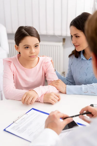 Ausgeschnittener Blick auf Arzt und Frau beruhigt Tochter während der Sprechstunde — Stockfoto