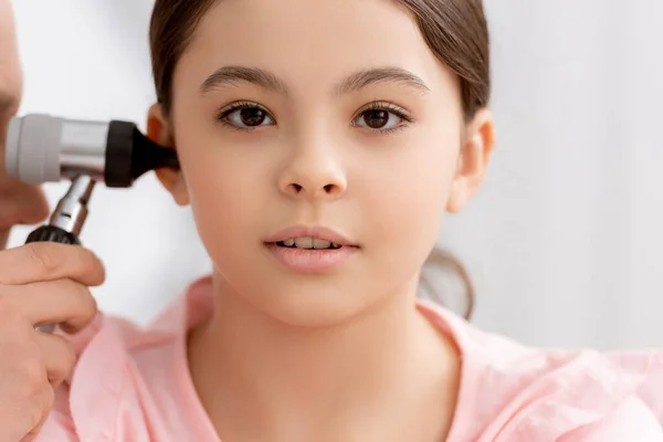 Vista recortada de ent médico examinando oreja de niño adorable con otoscopio - foto de stock