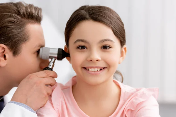 Ent médico examinando el oído de niño alegre con otoscopio - foto de stock